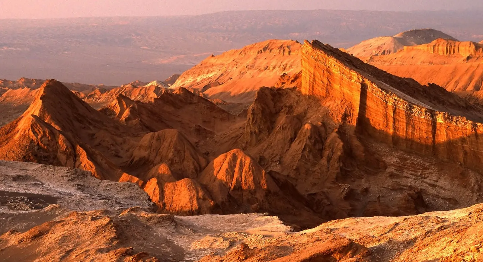 The jagged ridges of Valle de la Luna glow orange in late sun
