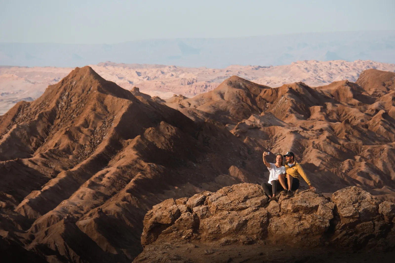 Two travellers take a selfie on a rock above the ridges of Valle de la Luna