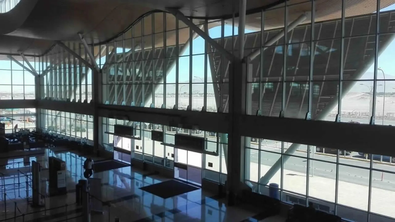 Tall glass walls and a sloping roof frame the hall inside El Loa Airport in Calama