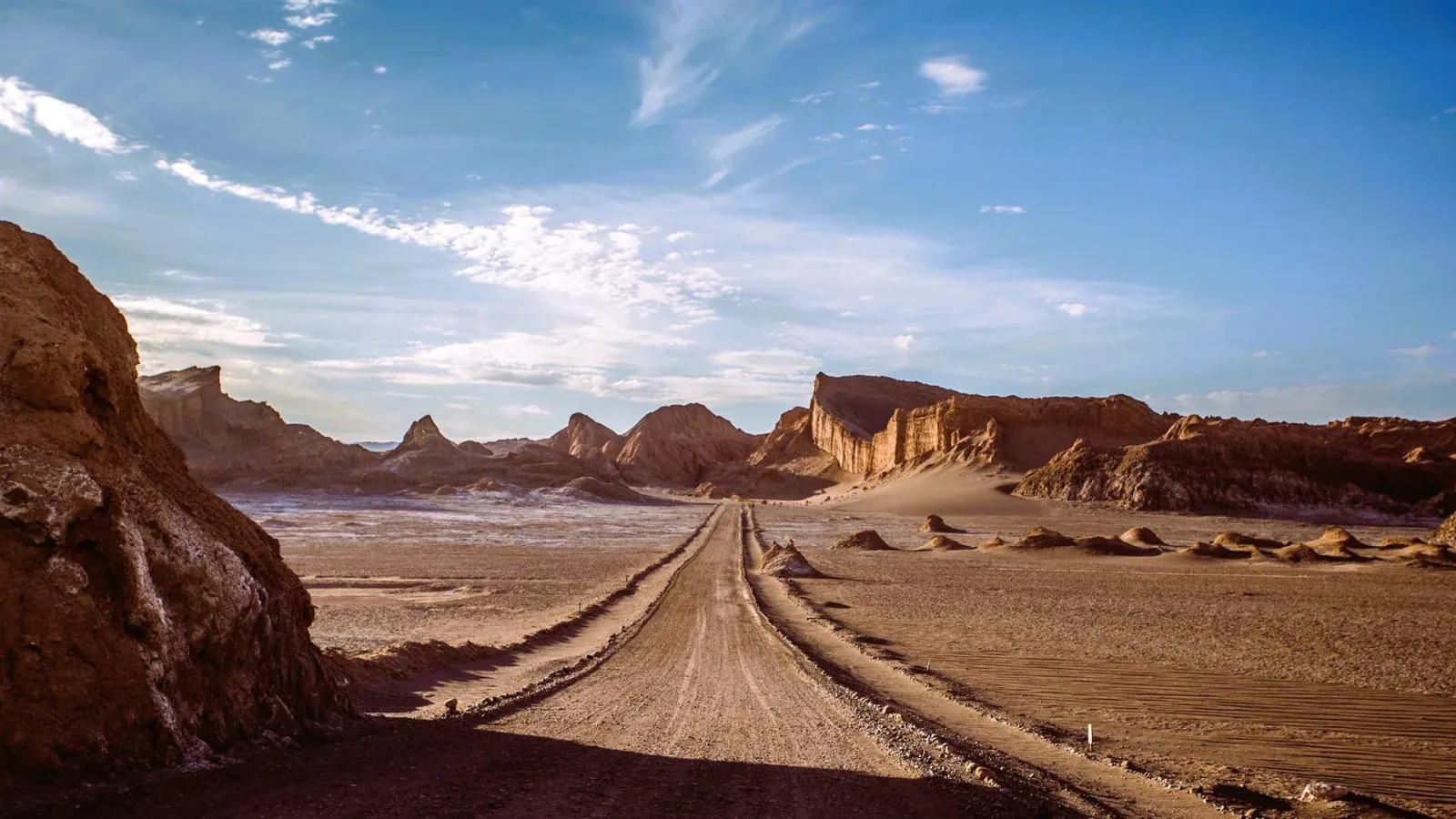 Dirt road running between eroded ridges in Valle de la Luna near San Pedro de Atacama
