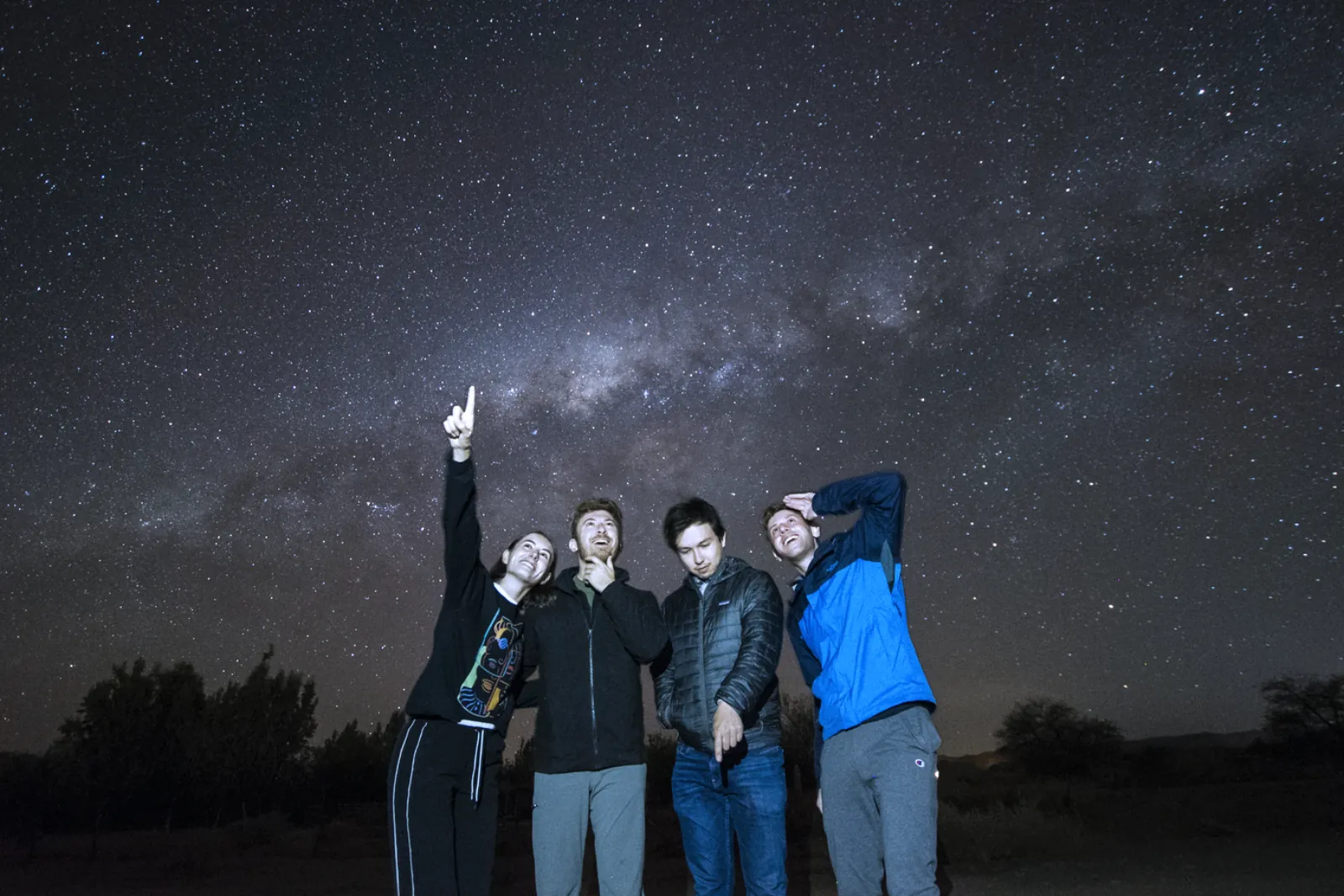 Guests in jackets gazing up at the Milky Way over the desert outside San Pedro de Atacama