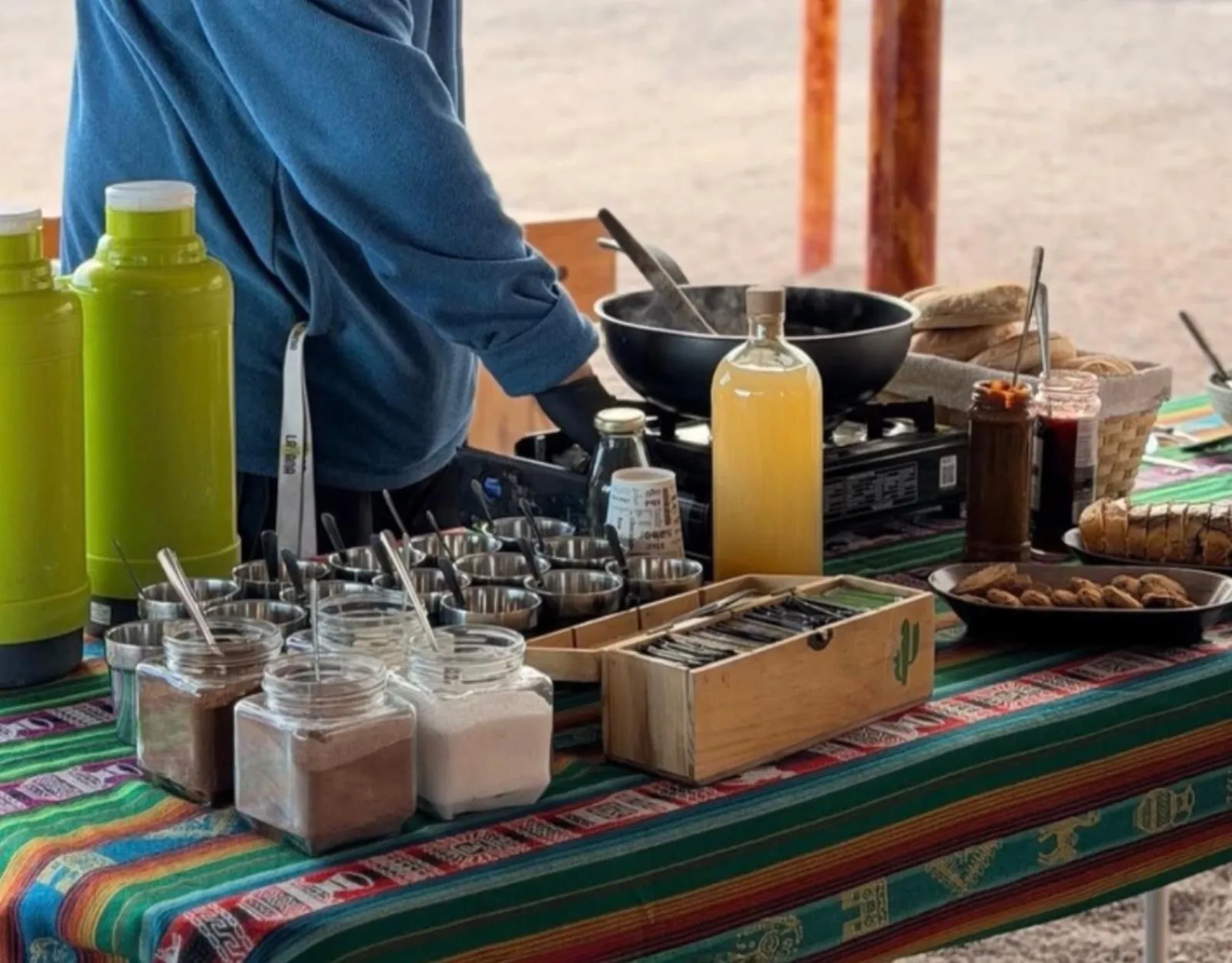 Breakfast laid out on a striped Andean cloth: thermoses, jars of coffee and sugar, juice and bread