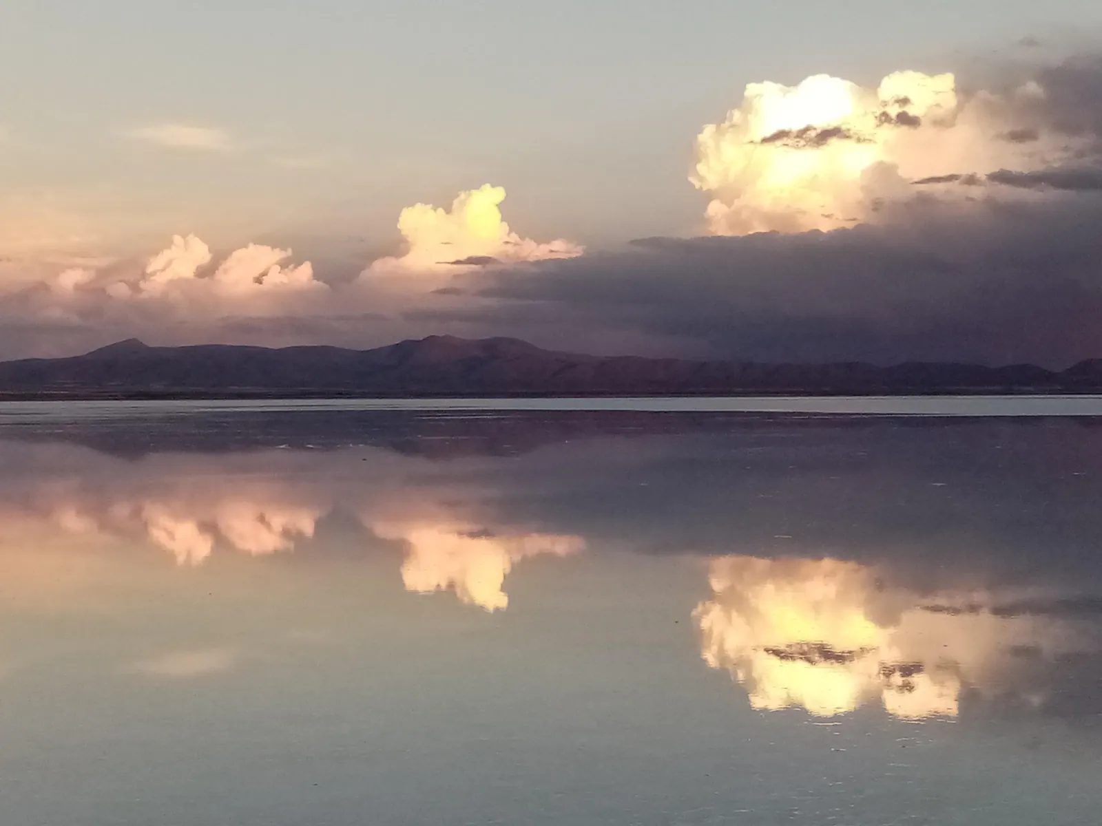 Clouds lit by evening sun mirrored on the flooded Salar de Uyuni